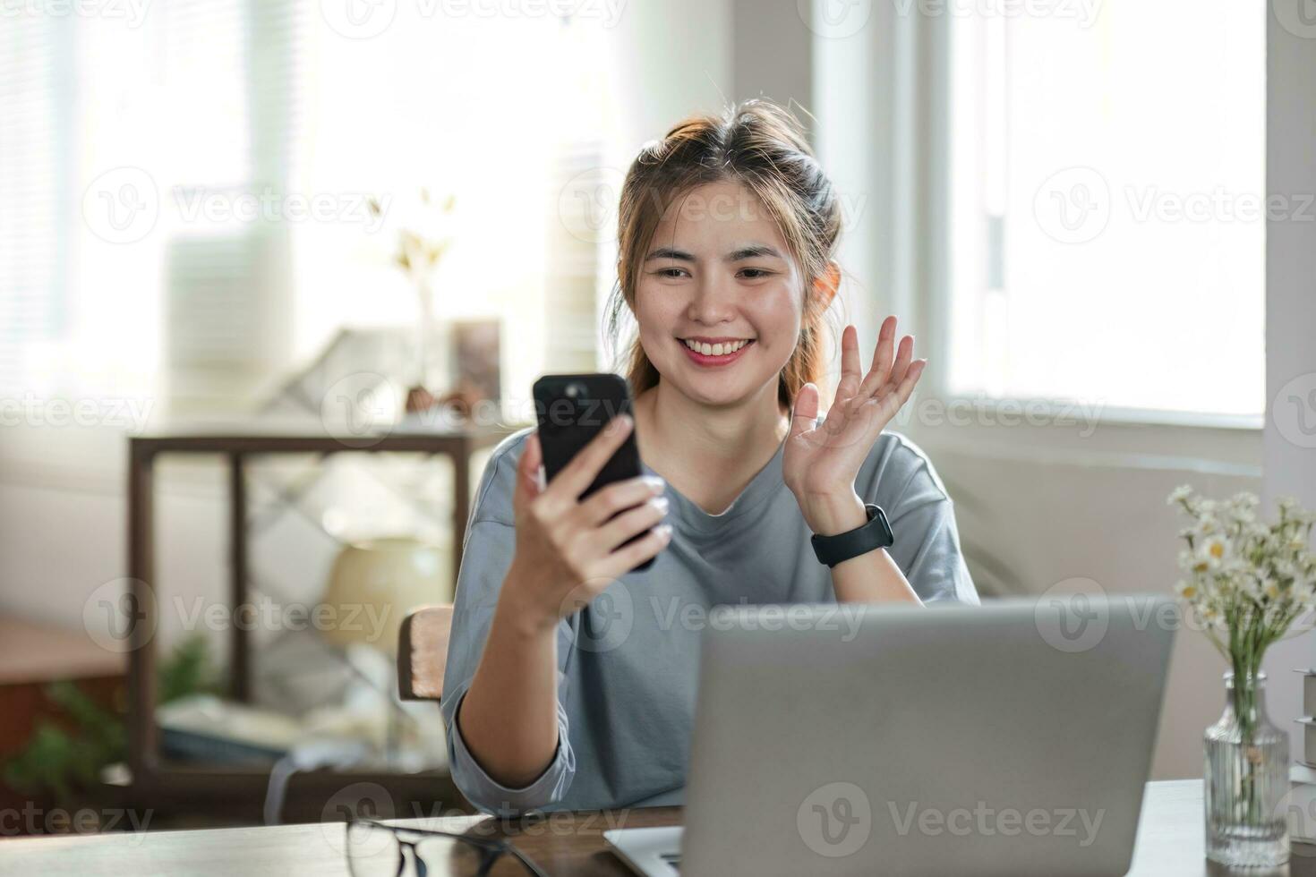 abbigliamento casual da donna d'affari freelance che utilizza laptop videoconferenza chiamata di lavoro con il cliente sul posto di lavoro nel soggiorno di casa. felice giovane ragazza asiatica rilassarsi seduto sulla scrivania fare un lavoro in internet. foto