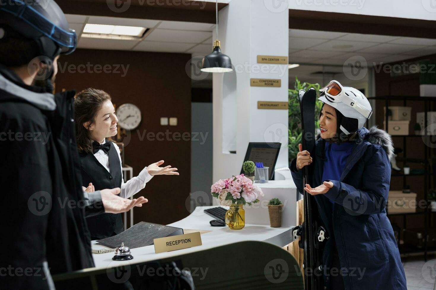 amichevole addetto alla reception assistere femmina turista con prenotazione e informazione su migliore sciare versante a inverno montagna ricorrere. giovane i viaggiatori trasporto sport invernali attrezzatura parlando con concierge. foto