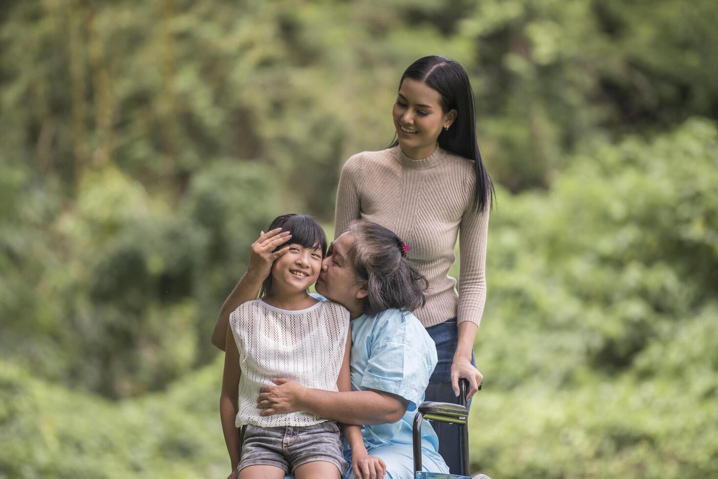 nonna felice in sedia a rotelle con sua figlia e suo nipote in un parco, vita felice tempo felice. foto