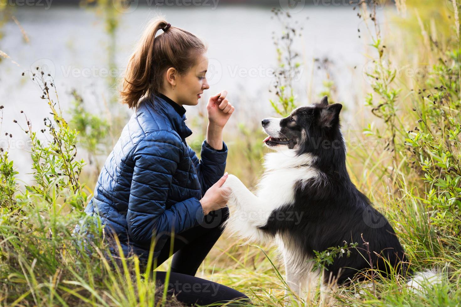 ragazza carina con una giacca blu si siede di fronte al suo cane foto