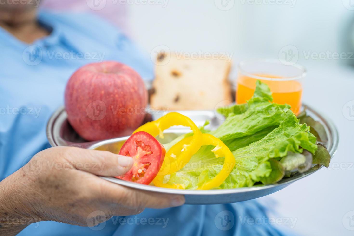 asiatico anziano o anziana signora anziana paziente che mangia colazione vegetale cibo sano con speranza e felice mentre è seduto e affamato sul letto in ospedale. foto