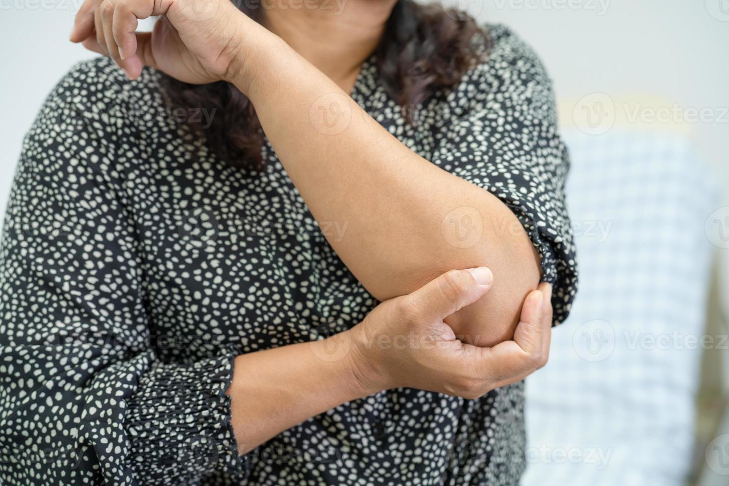 il paziente asiatico di mezza età della donna della signora tocca e sente dolore il gomito e il braccio, concetto medico sano. foto