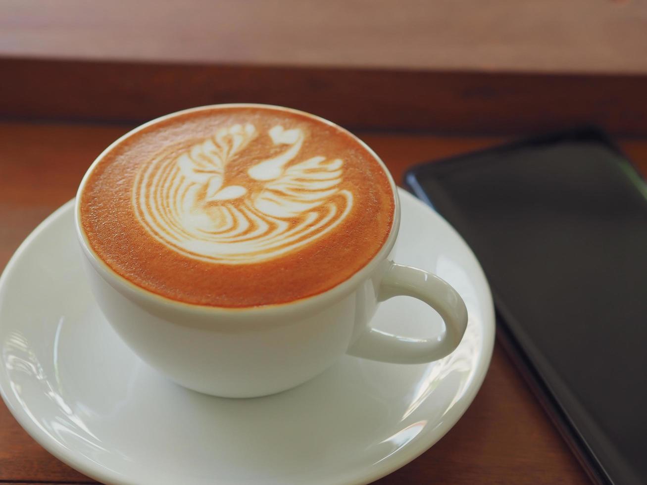latte o cappuccino con schiuma schiumosa, vista dall'alto della tazza di caffè sul tavolo nella caffetteria. foto