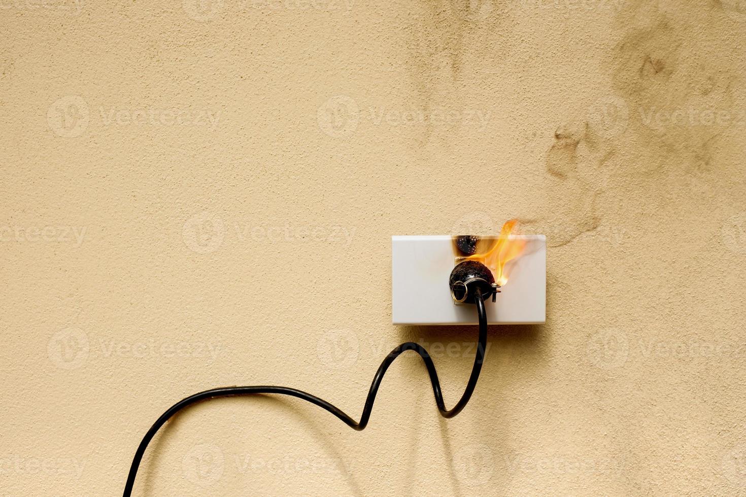in fiamme presa di corrente del cavo elettrico sullo sfondo del muro di cemento foto