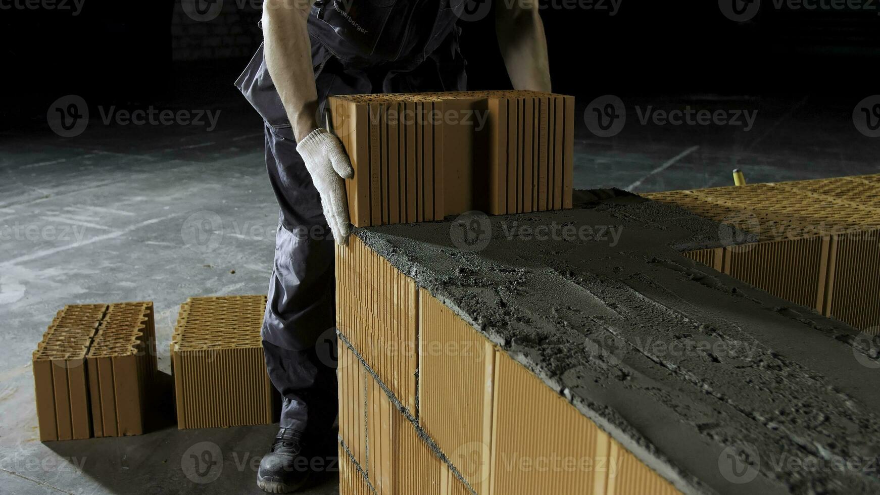 industriale muratore lavoratore collocazione mattoni su cemento mentre edificio muri. azione filmato. vicino su di un' uomo nel protettivo guanti mettendo pesante mattone bloccare per modulo un' strato. foto