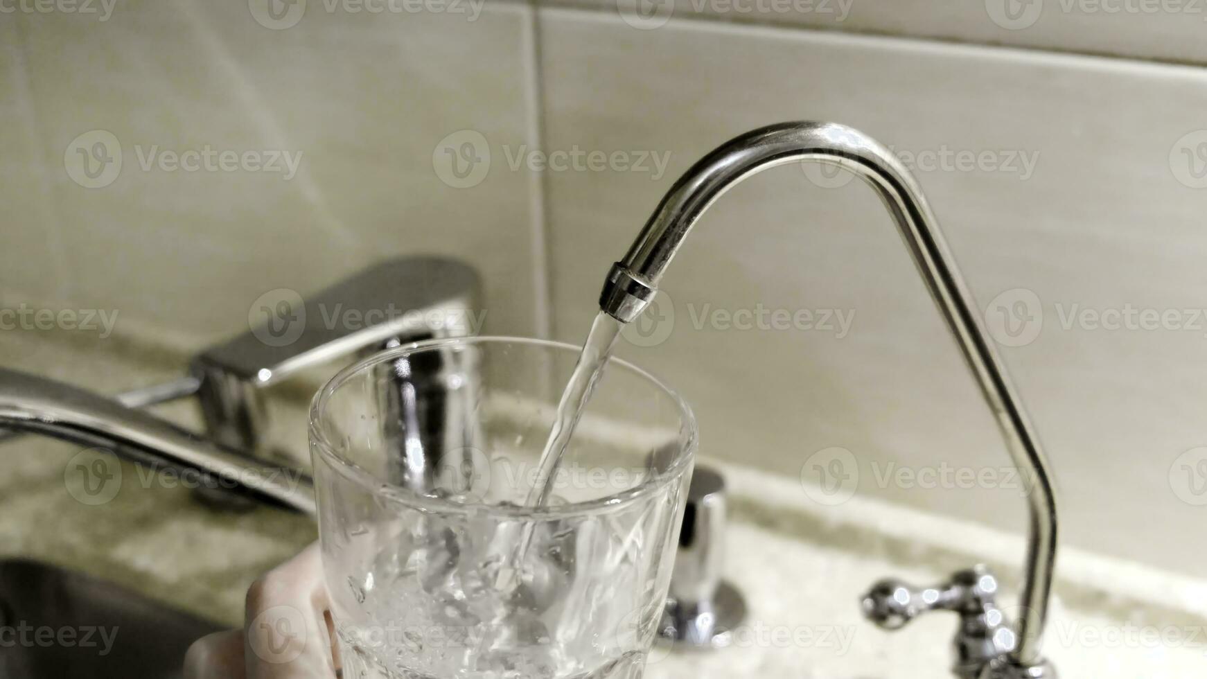 acqua essere versato in bicchiere a partire dal cucina rubinetto. concetto. avvicinamento di rubinetto acqua essere versato in un' bicchiere nel il cucina foto