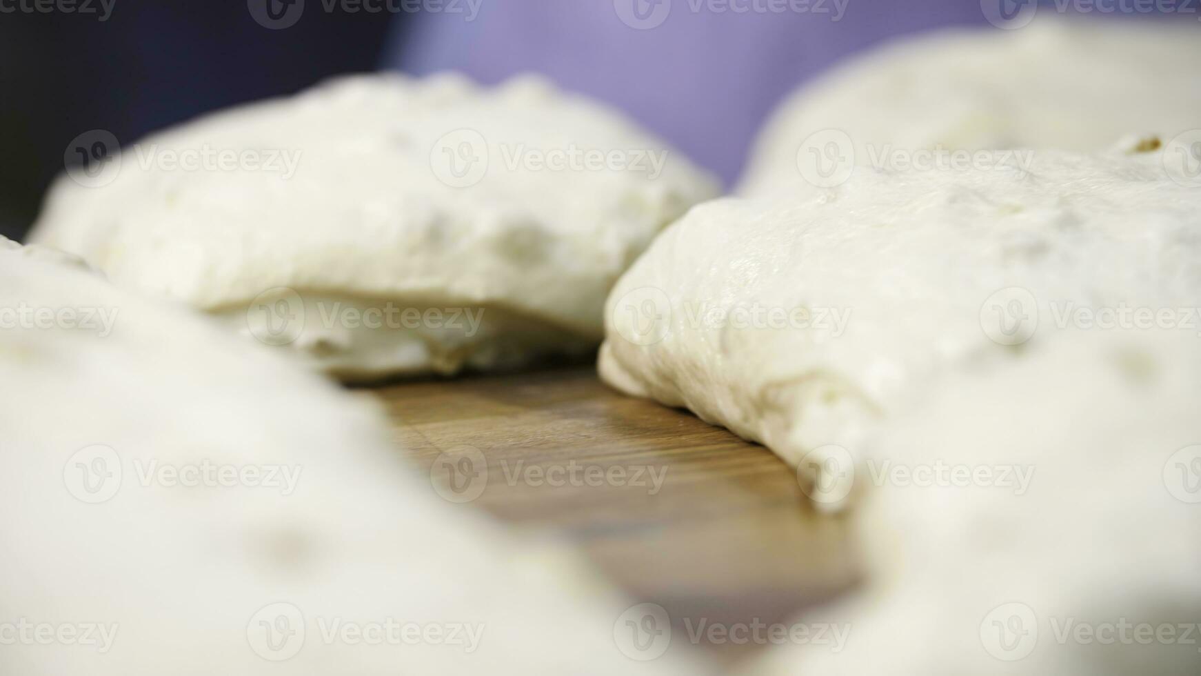 vicino su Visualizza per crudo pezzi di Pasticcino dire bugie su il di legno tavola su il tavolo. azione filmato. tradizionale delizioso Pasticcino pezzi con uva passa pronto per cottura al forno. foto