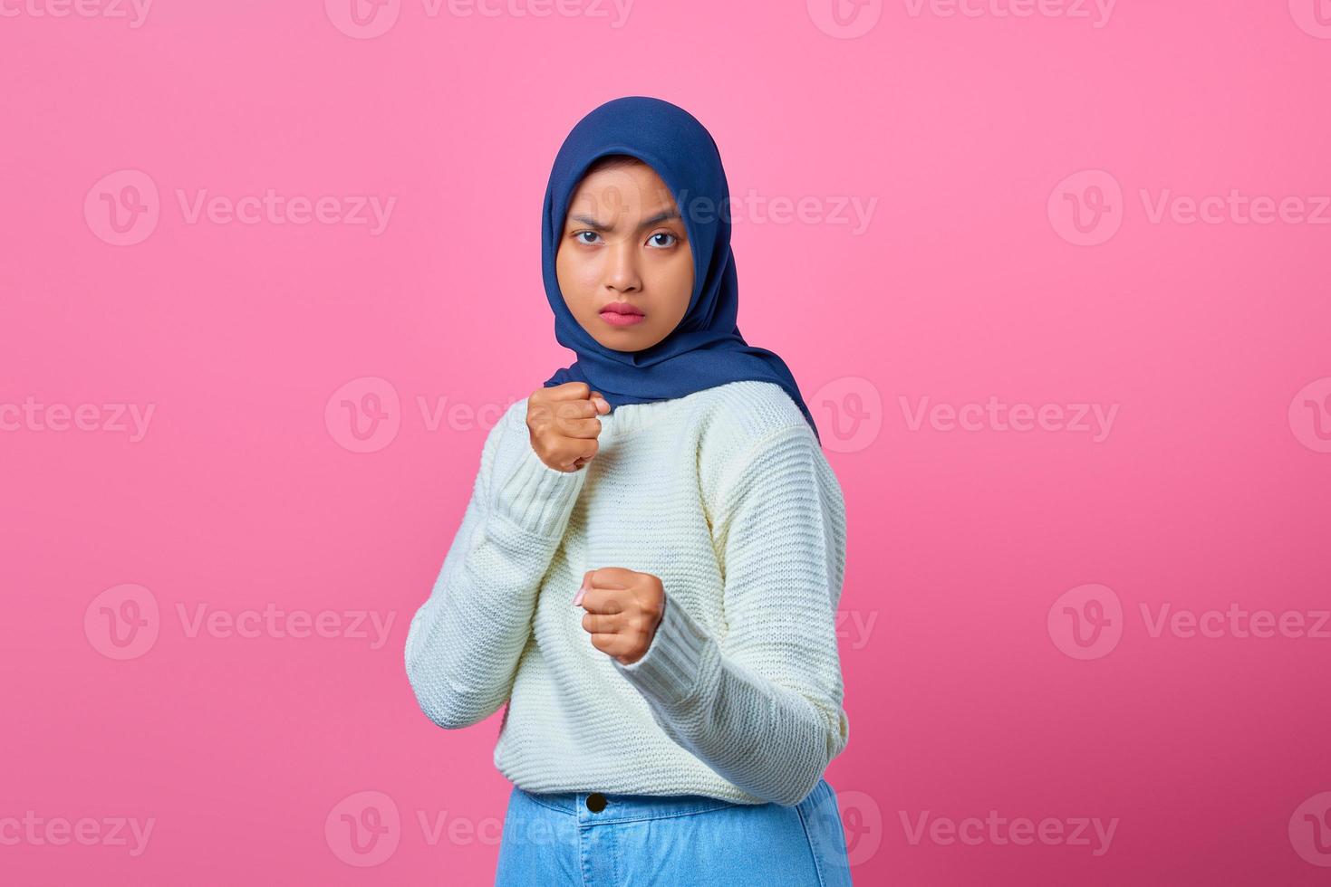 ritratto di giovane donna asiatica arrabbiata che mostra il gesto del pugile su sfondo rosa foto