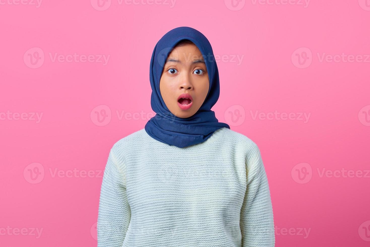 ritratto di giovane donna asiatica sorpresa che guarda la macchina fotografica su sfondo rosa foto