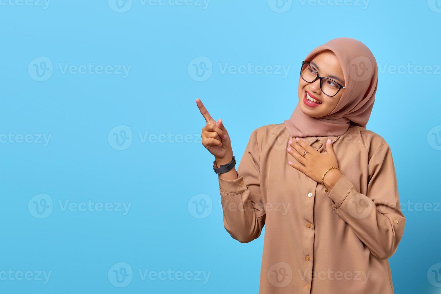 ritratto di giovane donna asiatica sorridente che indica lo spazio della copia con il dito foto