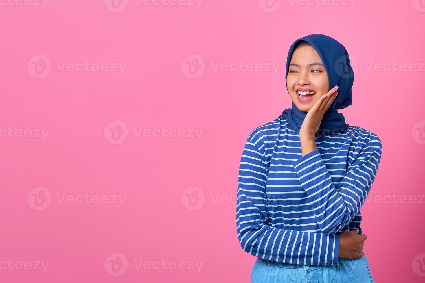 ritratto di giovane donna asiatica sorridente con la mano sulla guancia e guardando al lato foto