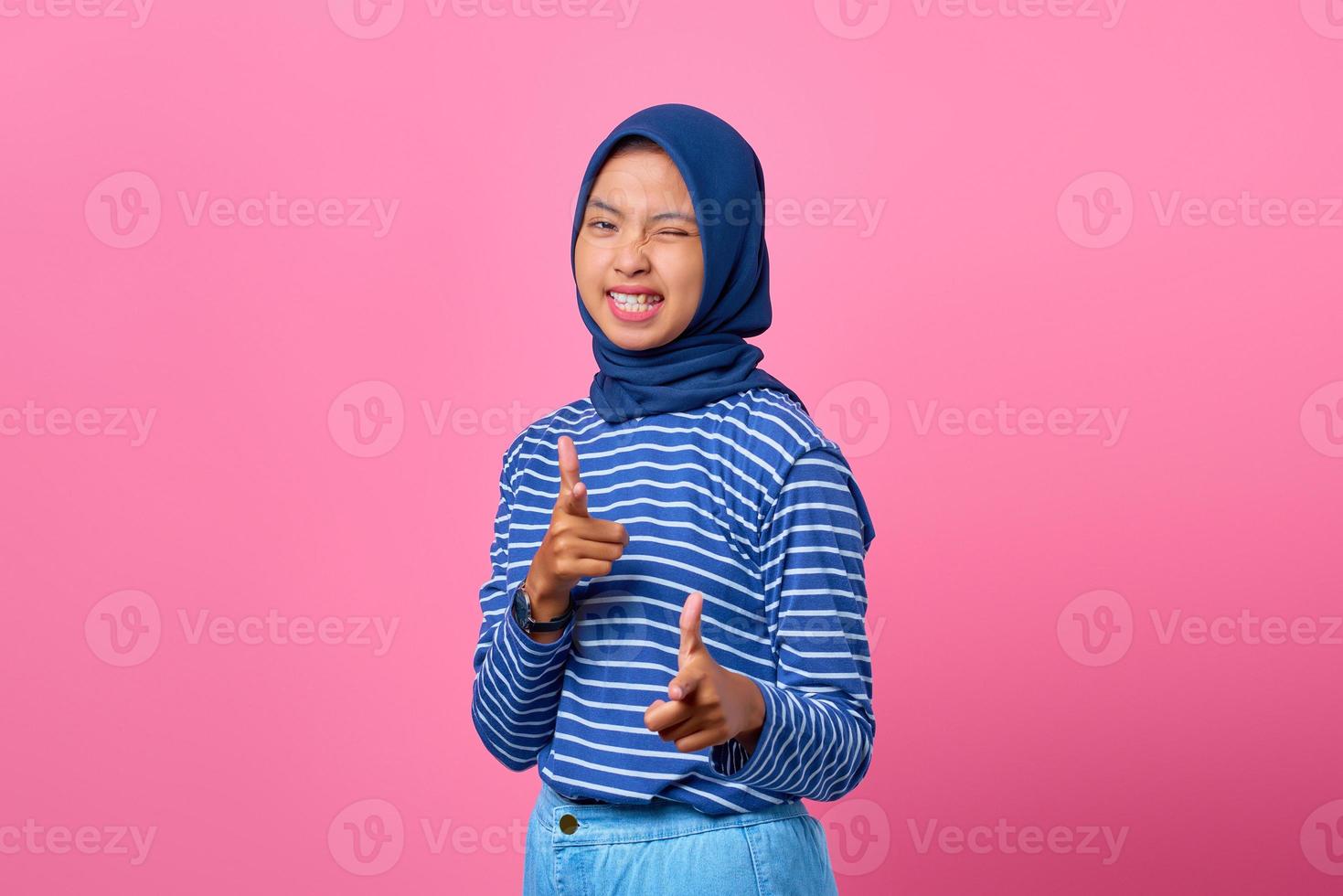ritratto di giovane donna asiatica eccitata che punta il dito verso la telecamera su sfondo rosa foto