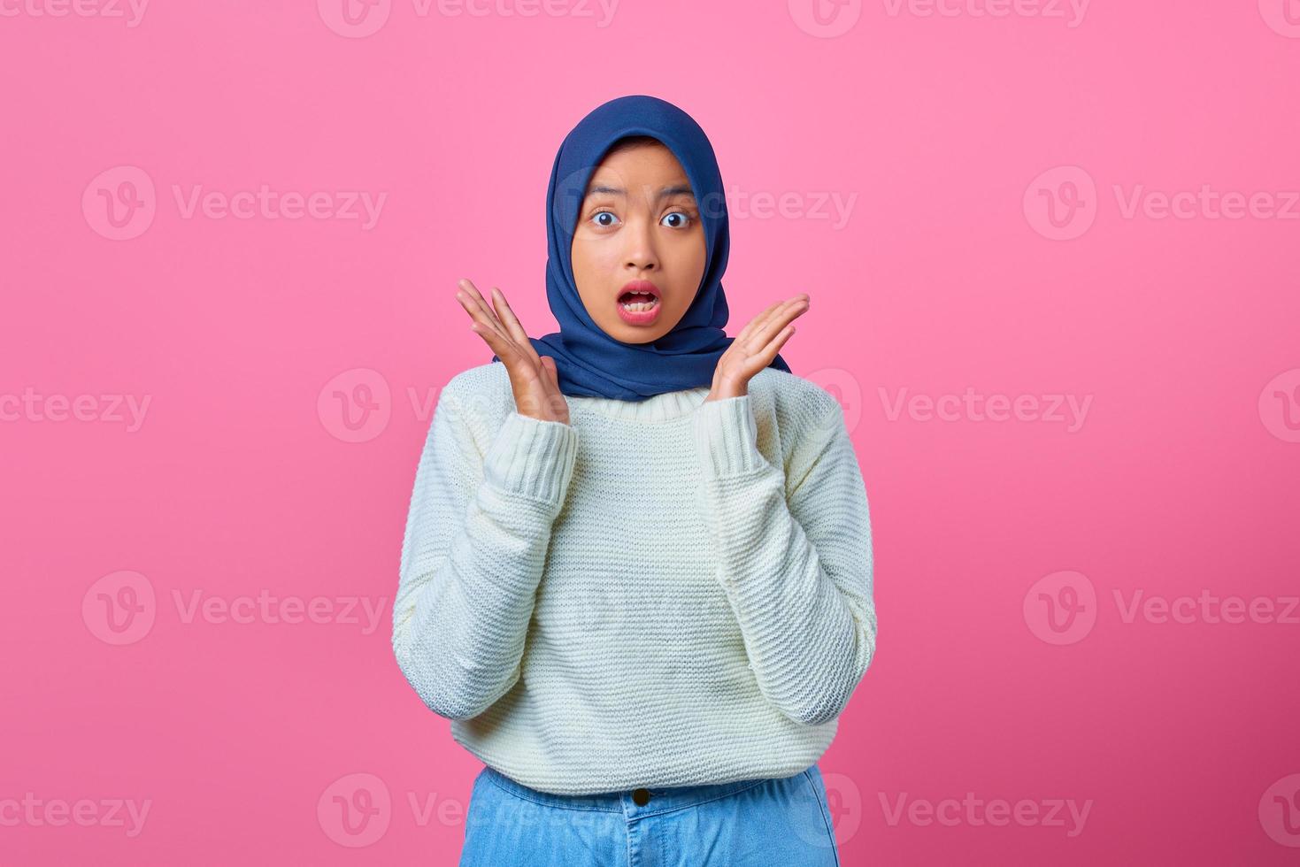 ritratto di giovane donna asiatica sorpresa che guarda la macchina fotografica su sfondo rosa foto