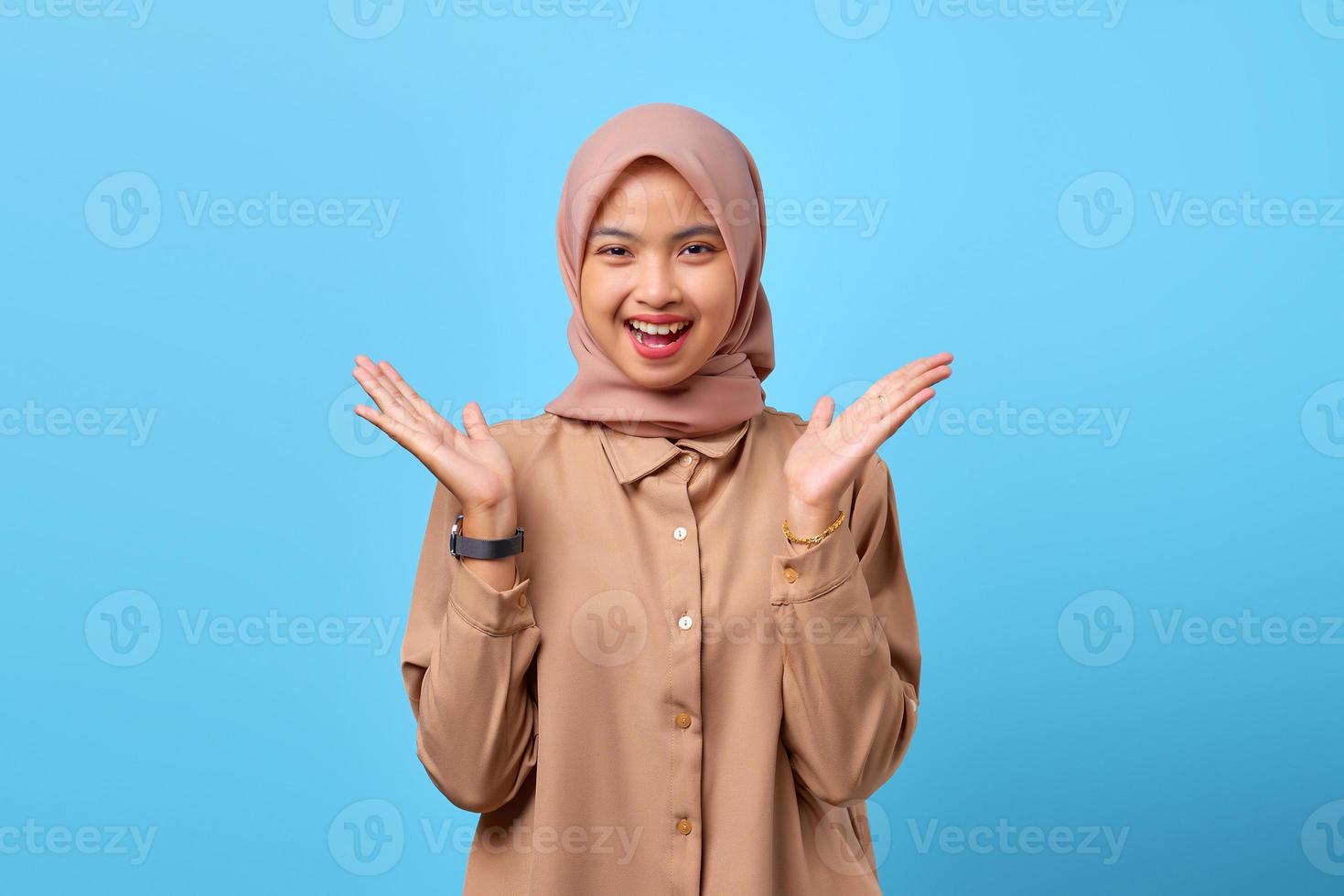 ritratto di giovane donna asiatica sorpresa ha alzato la mano con la bocca aperta su sfondo blu foto