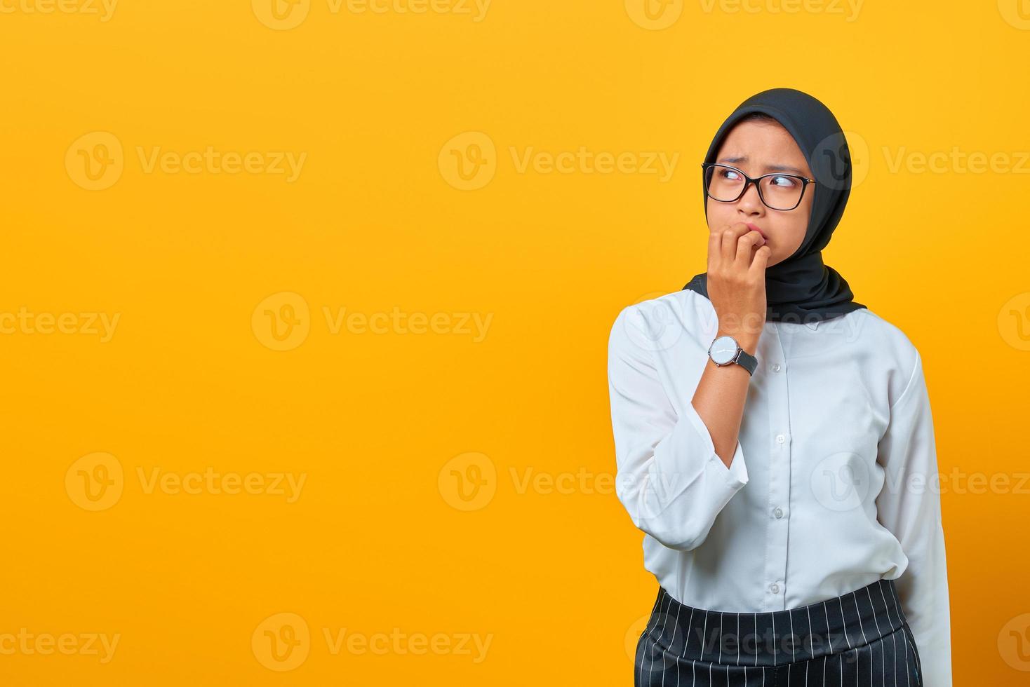 Ansioso preoccupato giovane donna asiatica spaventata da qualcosa di isolato su sfondo giallo foto