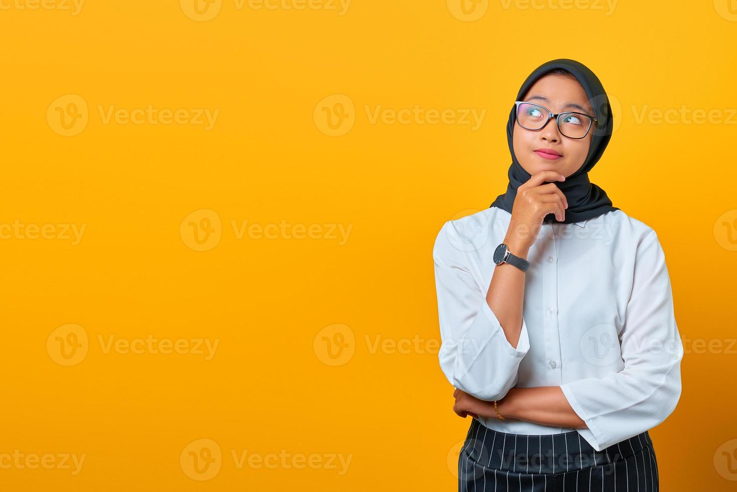 pensierosa giovane donna asiatica sembra seriamente pensare a una domanda su sfondo giallo foto