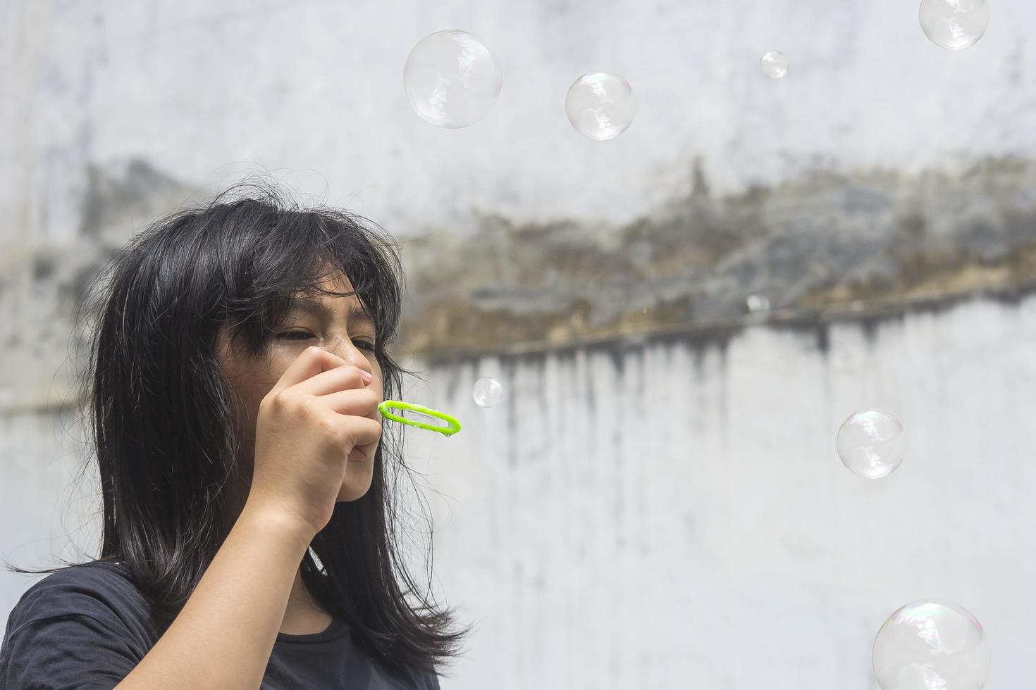 una ragazza che tiene in mano un creatore di bolle e le fa esplodere. foto