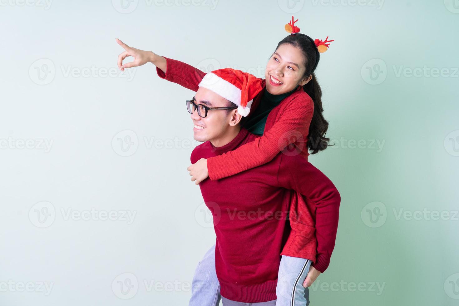 giovane coppia asiatica in posa su sfondo verde con concetto di natale foto