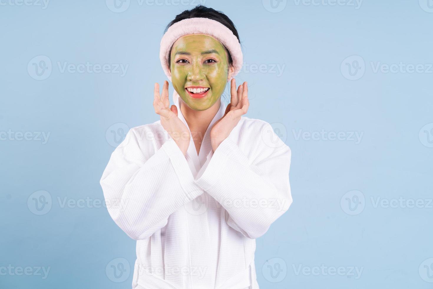 giovane donna asiatica che indossa accappatoio su sfondo blu foto