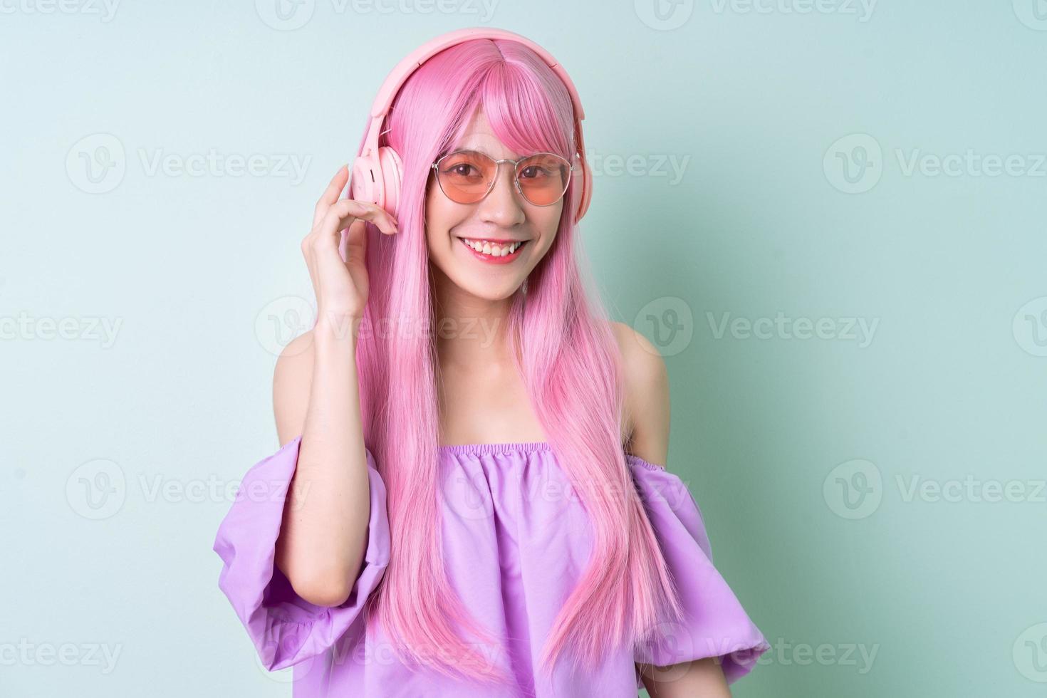 giovane donna asiatica con i capelli rosa in posa su sfondo verde foto