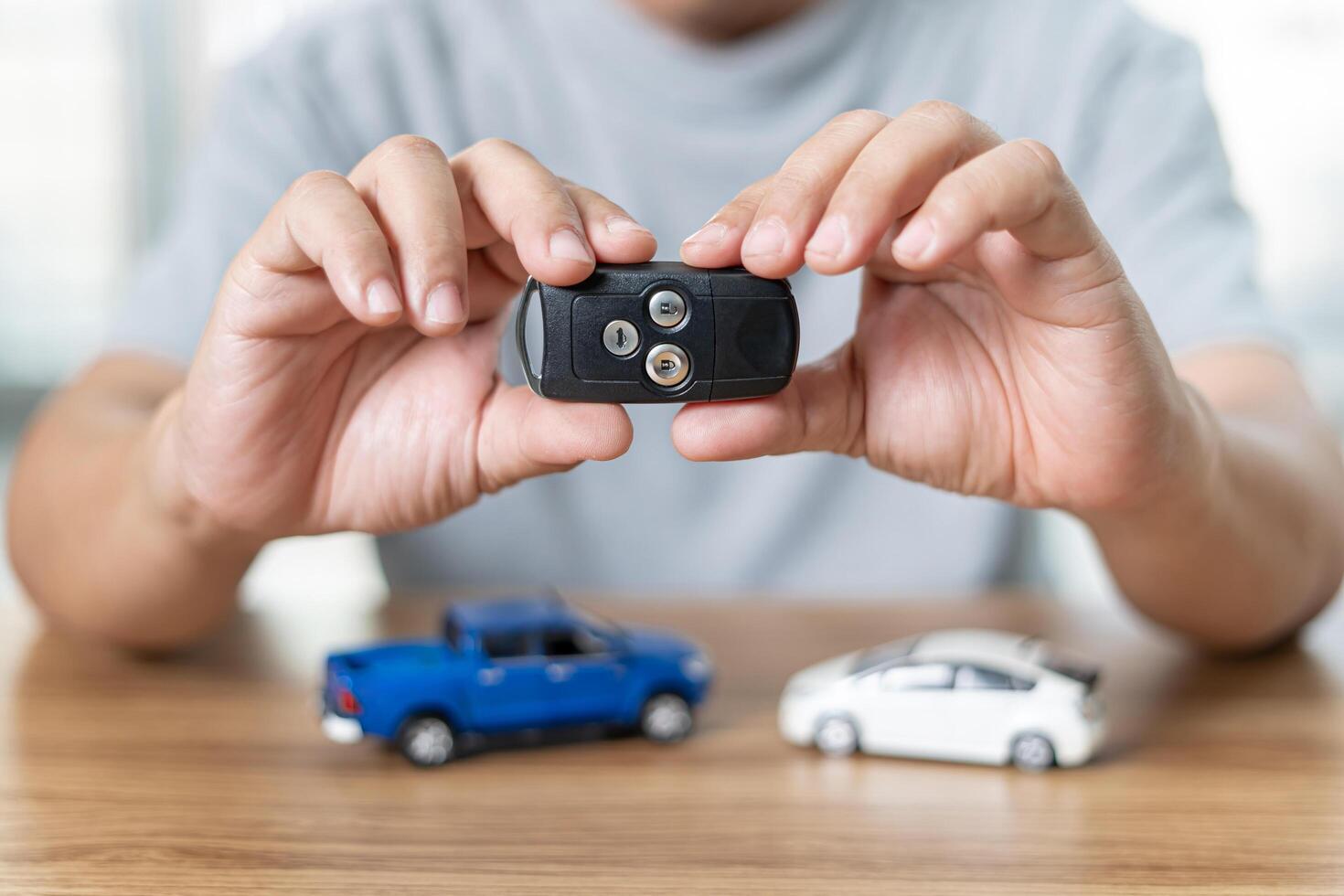 uomo Tenere a distanza controllo di auto per serratura e sbloccare auto nel il antifurto sistema e modello giocattolo un' auto su legna pavimento foto