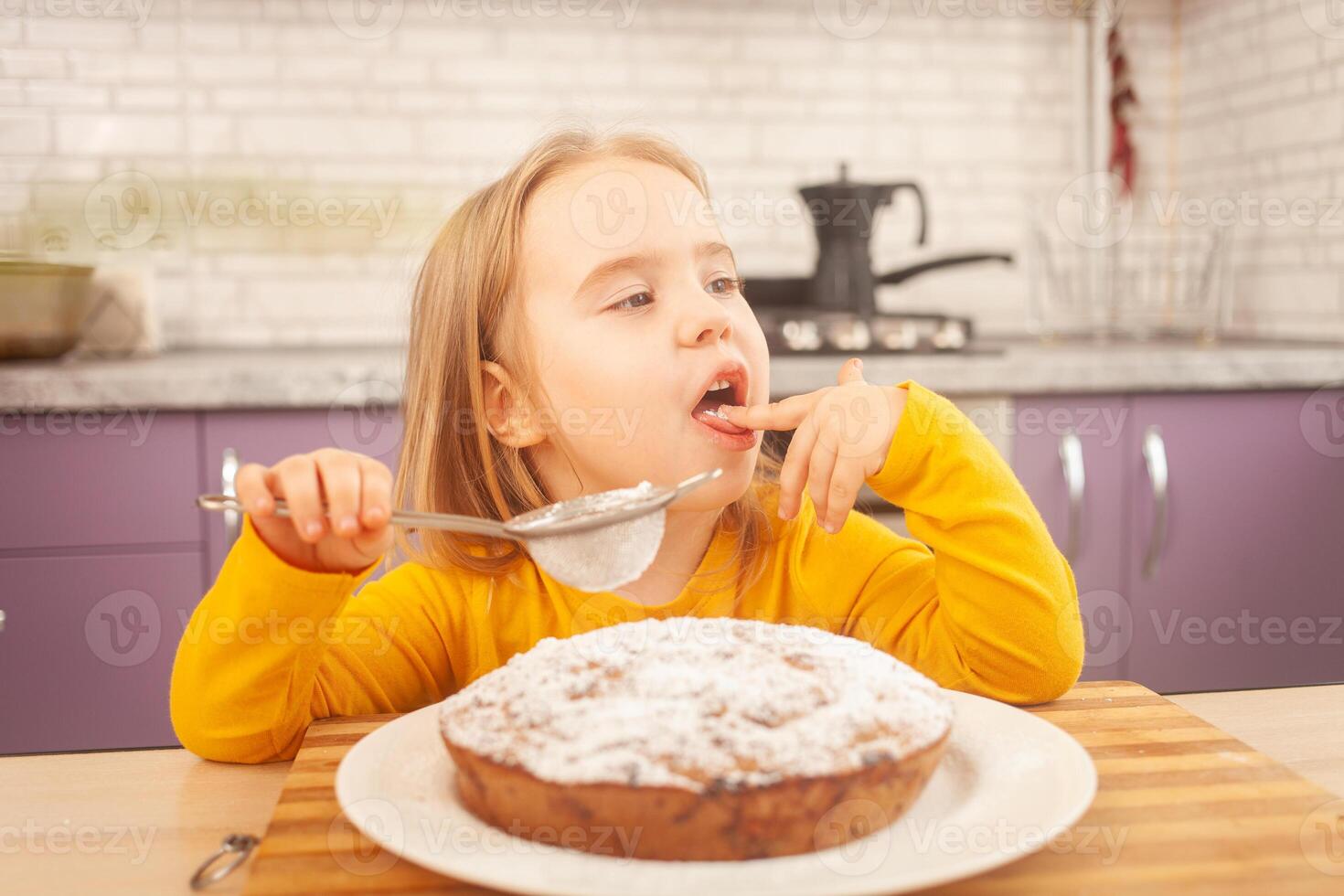 divertente poco ragazza bambino degustazione dolce in polvere zucchero, decorazione torta, avendo divertimento e sorridente, cucinando nel cucina. lavanda. foto