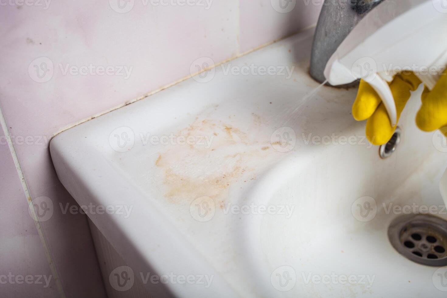 domestica con gomma da cancellare guanto pulizia rubinetto e lavello. foto