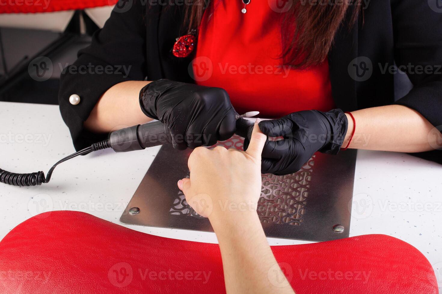 il manicure detiene mani di il cliente nel bellezza salone su del desktop per manicure con chiodo lucidi, tovaglioli, creme e illuminazione strumenti foto