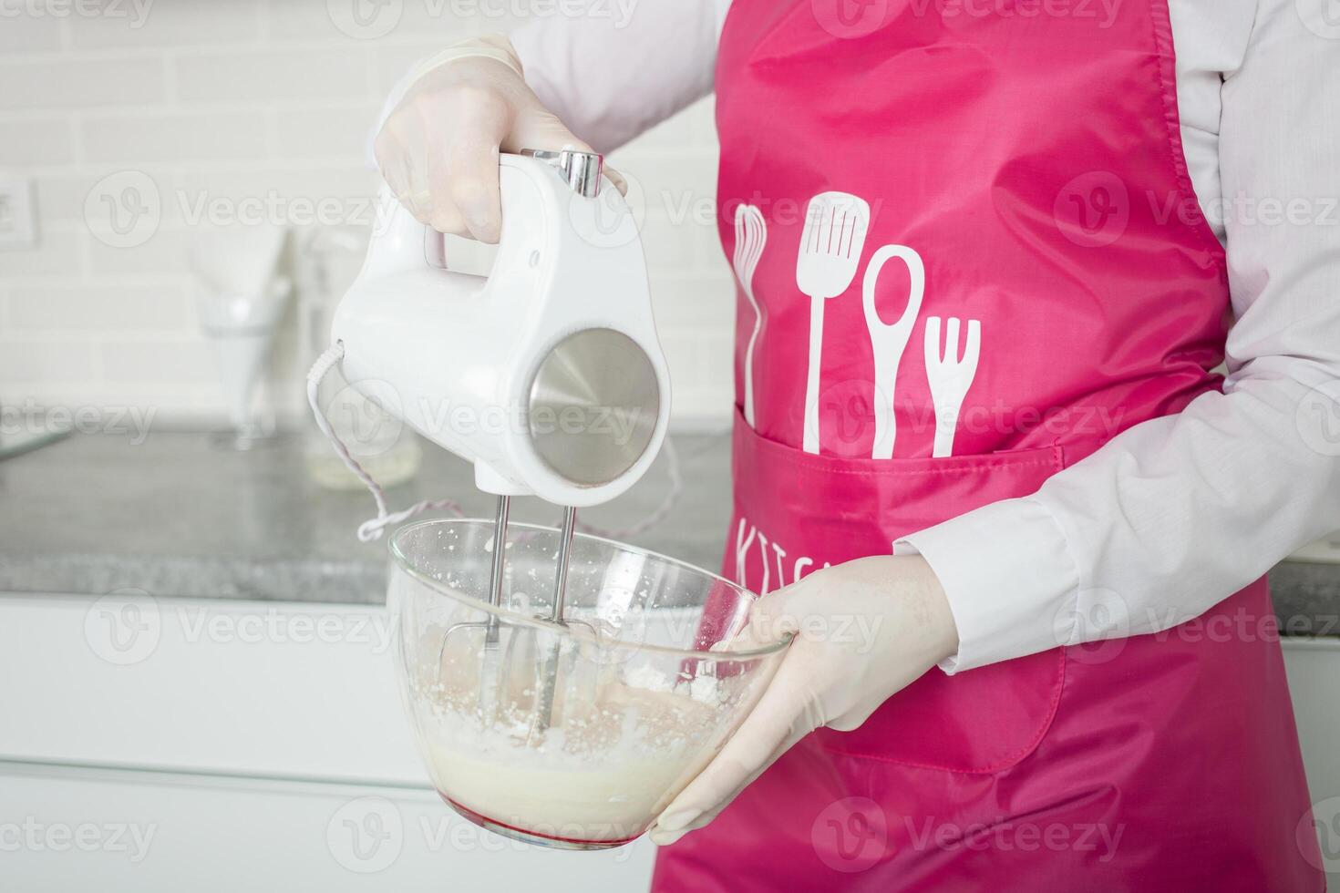 pasticciere battiti crema con mano miscelatore nel bicchiere ciotola. preparazione di dolci. foto