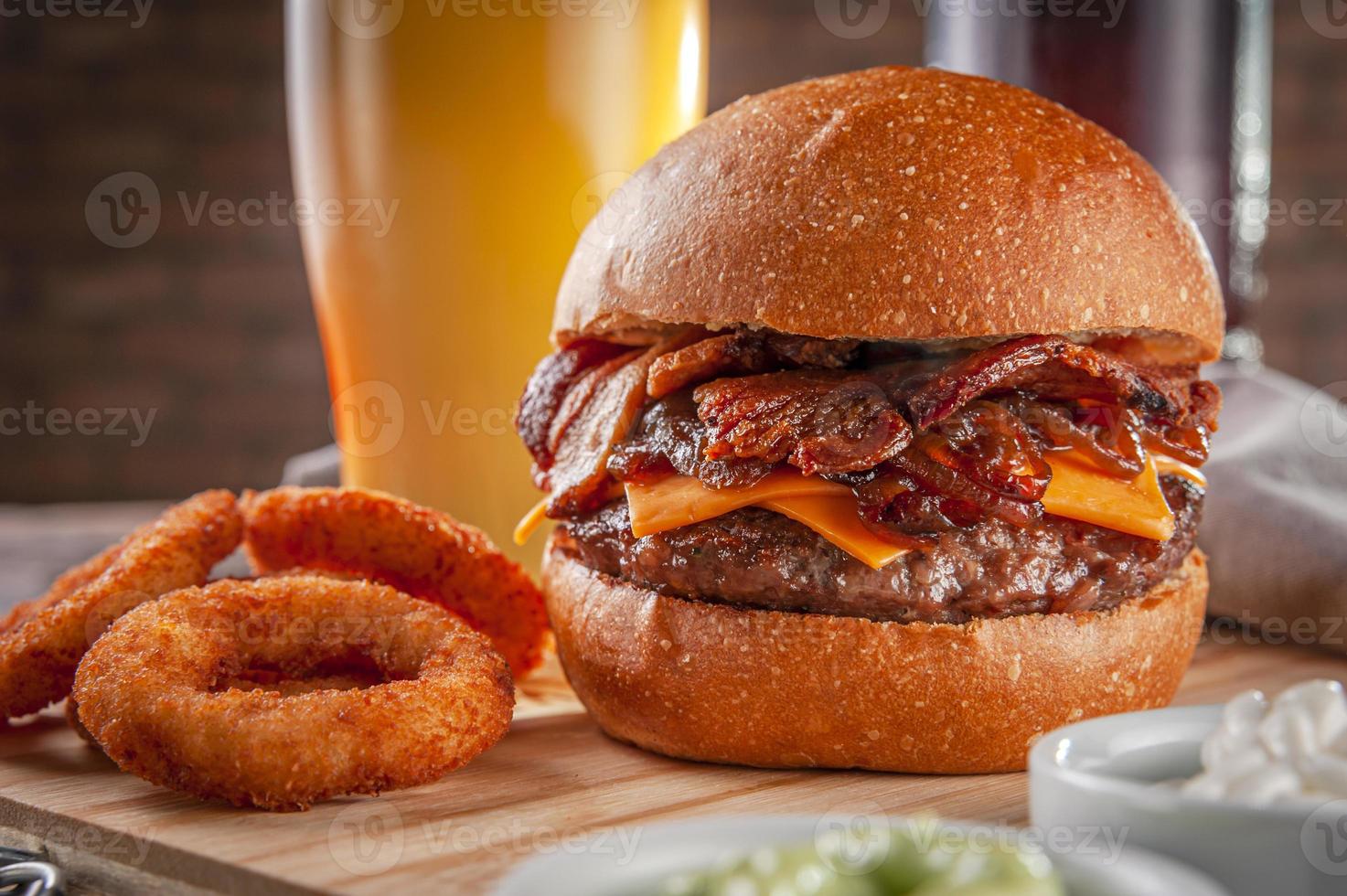 delizioso hamburger di pancetta con anelli di cipolla e birra. foto