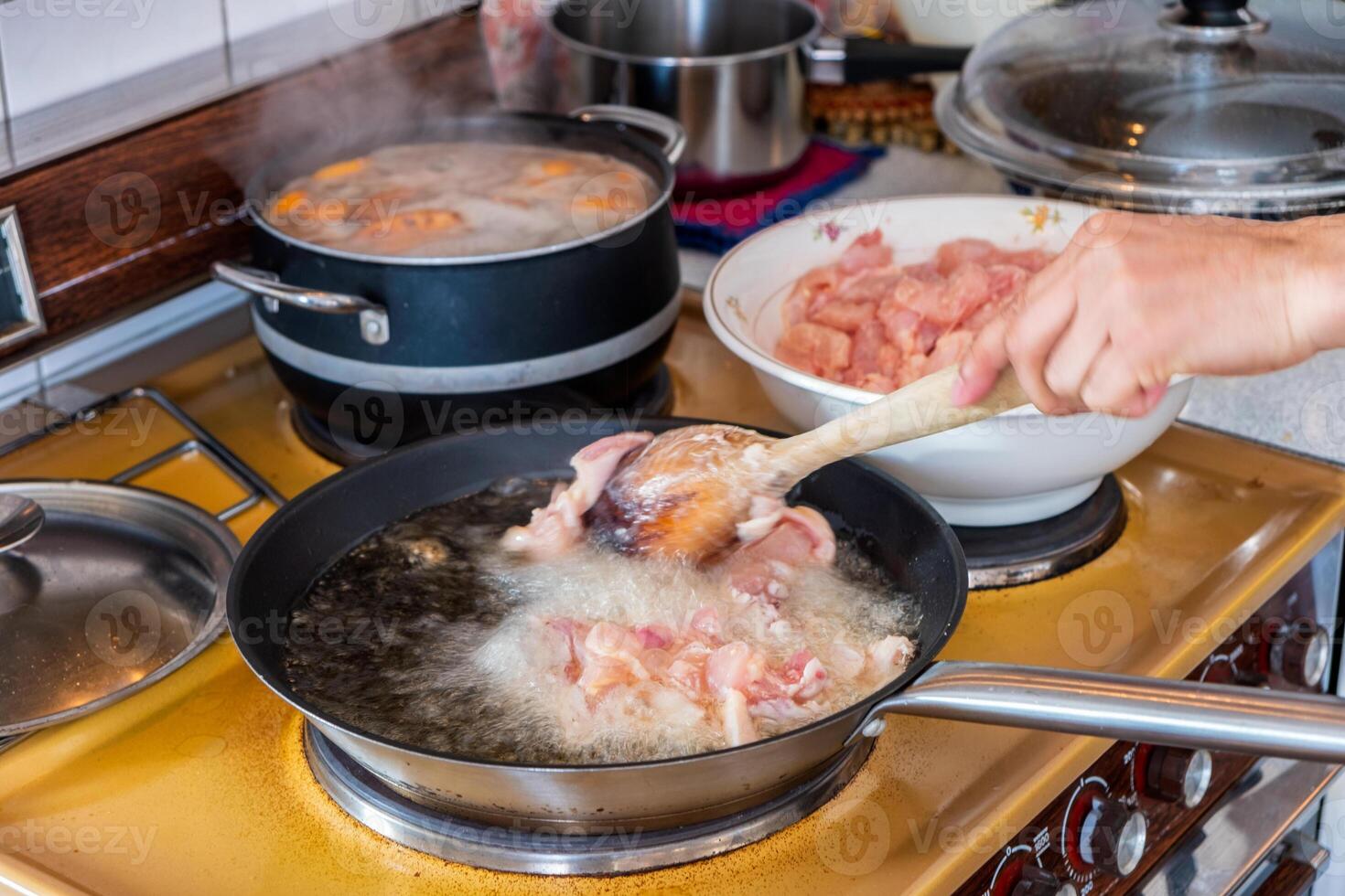 capocuoco cucinando pollo frittura Bollire nel olio con tegame foto