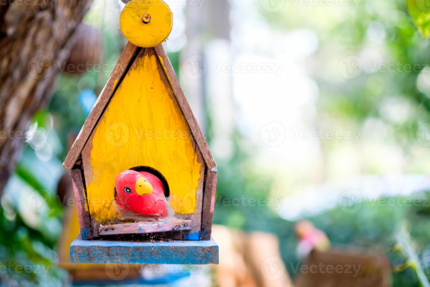 giallo di legno casa nido uccello con rosso uccello fatto a mano sospeso su sfondo foto