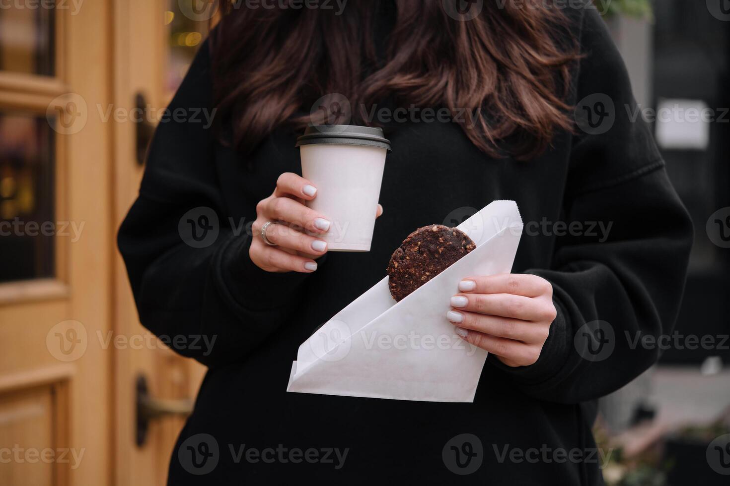 donna Tenere un' boccale di caffè e fiocchi d'avena biscotti nel sua mani foto