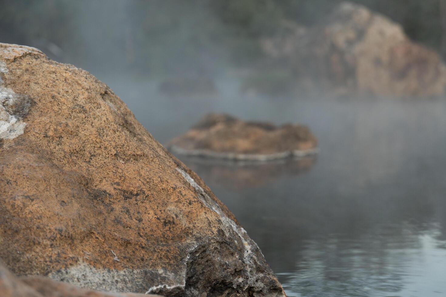 rocce sporgente sopra il superficie di il acqua nel chaeson caldo primavera. con un' magro strato di vapore. a chae figlio nazionale parco Tailandia. foto