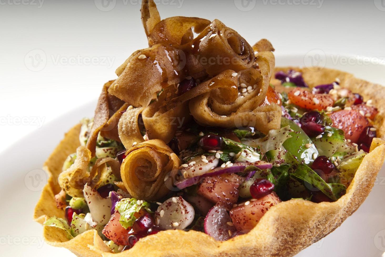 delizioso fattoush o insalata araba con crostini di pita, verdure fresche ed erbe aromatiche, su piastra bianca. insalata di pane mediorientale. ricetta genuina facile e sana. foto