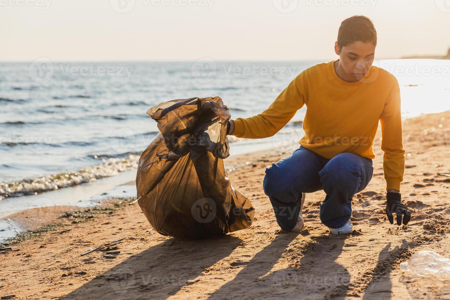 terra giorno. volontari attivisti squadra raccoglie spazzatura pulizia di spiaggia costiero zona. donna mette plastica spazzatura nel spazzatura Borsa su oceano costa. ambientale conservazione costiero zona pulizia foto