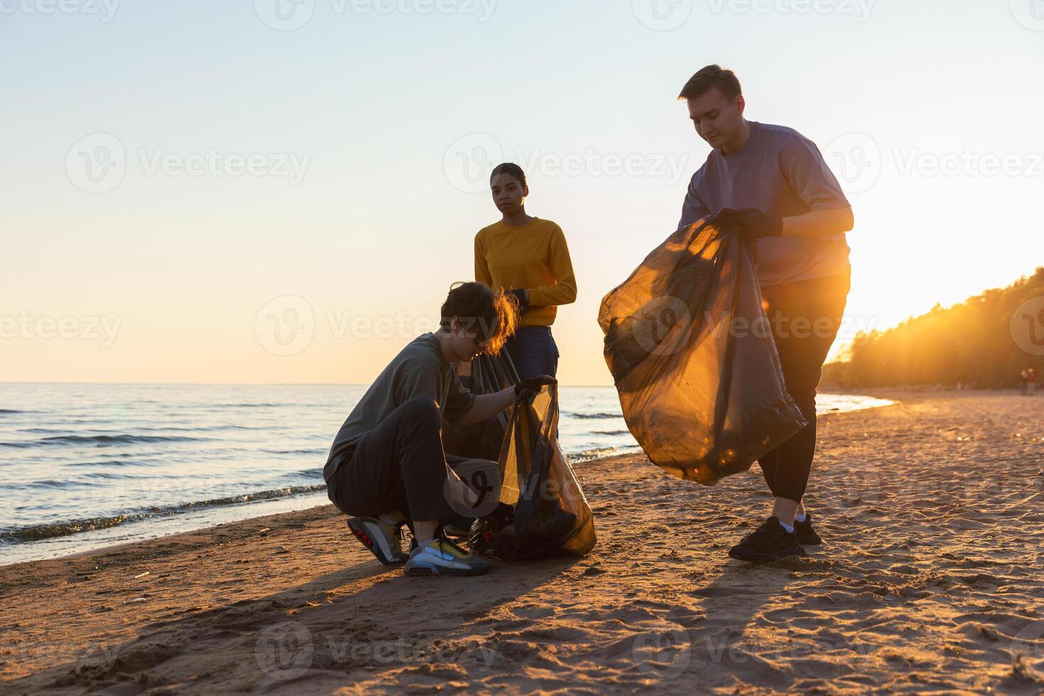 terra giorno. volontari attivisti raccoglie spazzatura pulizia di spiaggia costiero zona. donna e mans mette plastica spazzatura nel spazzatura Borsa su oceano costa. ambientale conservazione costiero zona pulizia foto