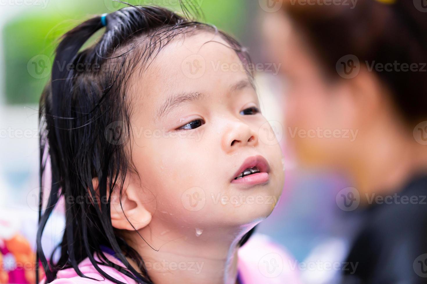 ragazza asiatica del bambino che gioca acqua in piscina con la famiglia. bambino faccia felice che si diverte con i viaggi in vacanza. giorno d'estate. bambini dai 4 ai 5 anni. foto