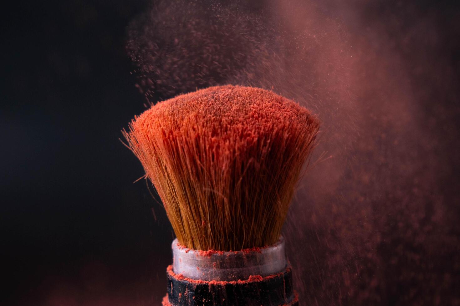 cosmetico spazzola con pastello rosa cosmetico polvere diffusione su nero sfondo. trucco spazzola con rosa polvere esplosione vicino su. foto