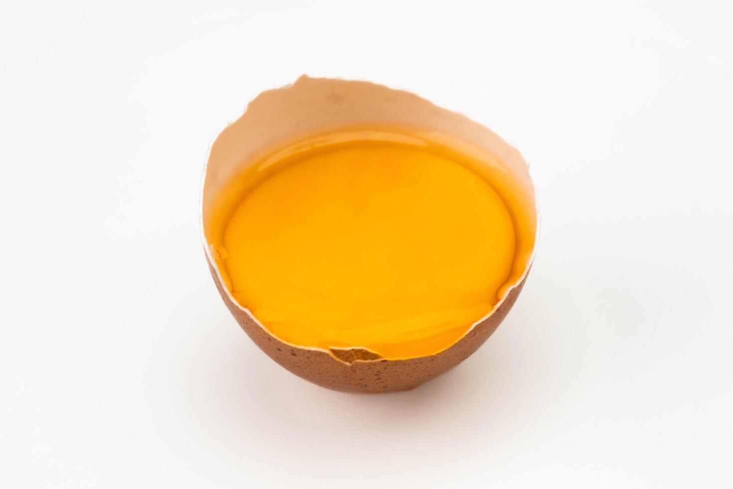rotto uovo nel metà guscio d'uovo isolato su bianca sfondo. vicino su di rotto uovo foto