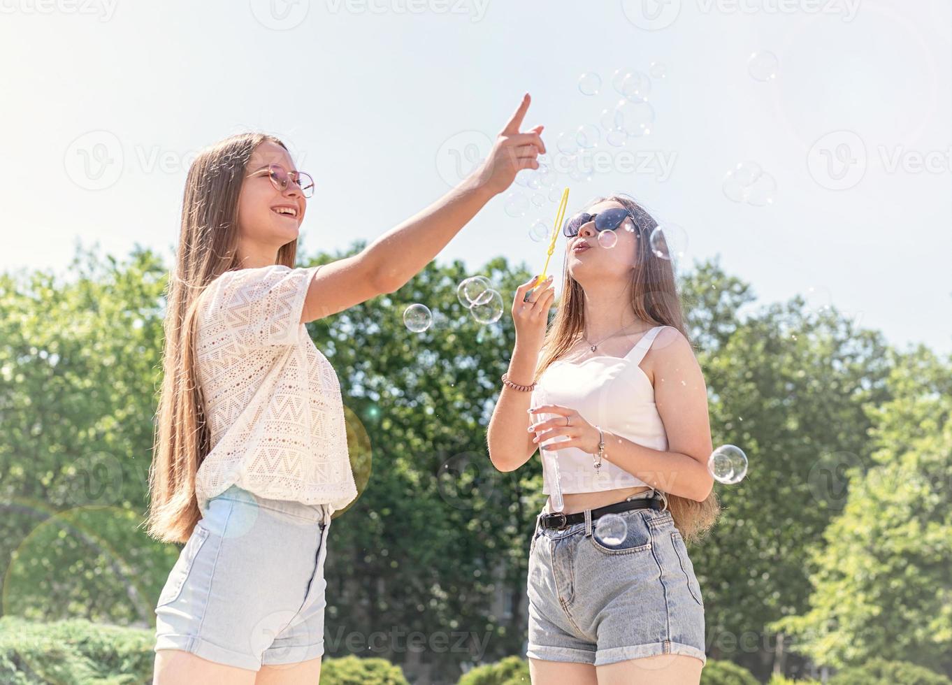 due amici si divertono fuori a fare bolle di sapone in un giorno d'estate foto