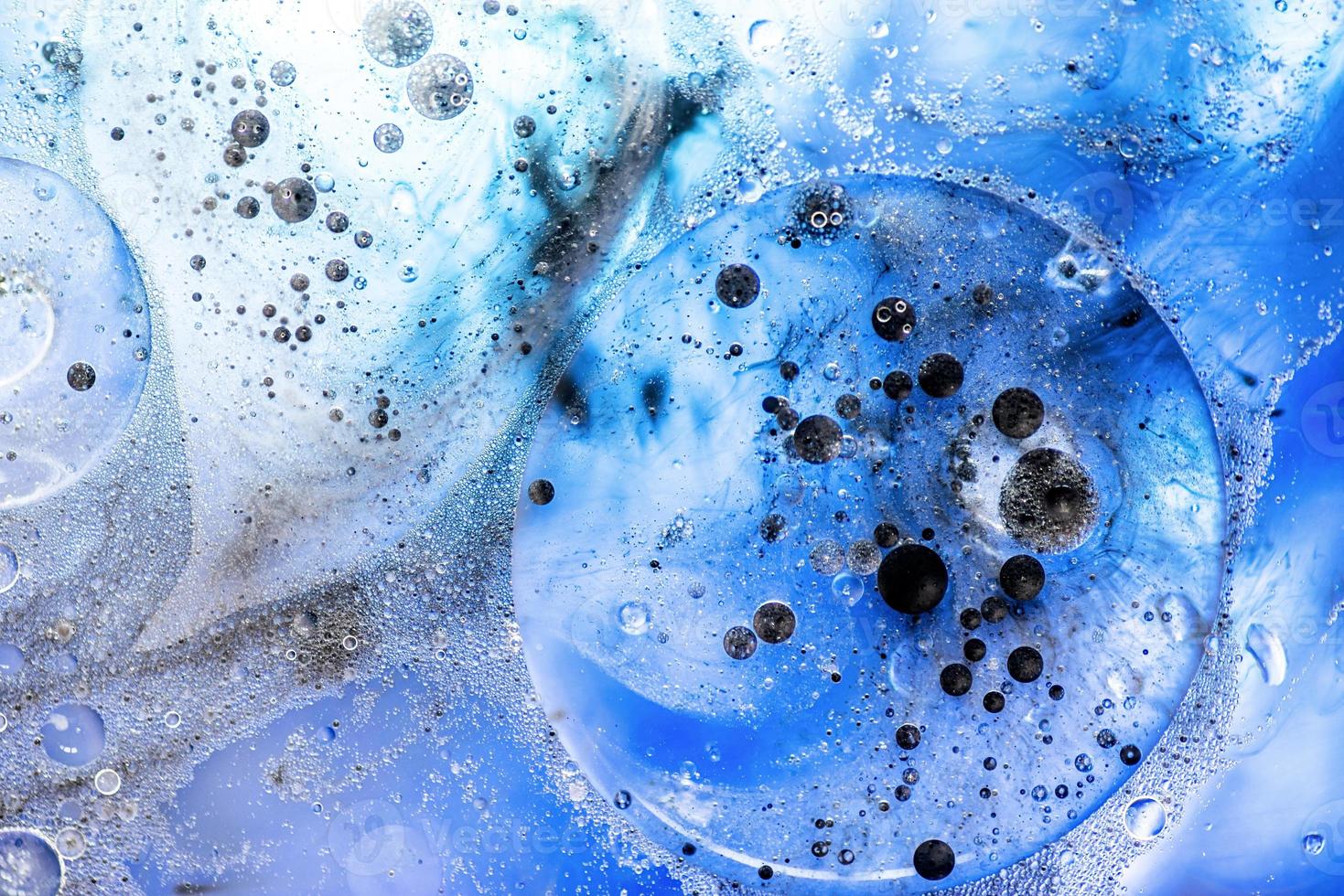 bolle blu brillante con inchiostro nero sulla superficie dell'acqua in sfondo astratto foto