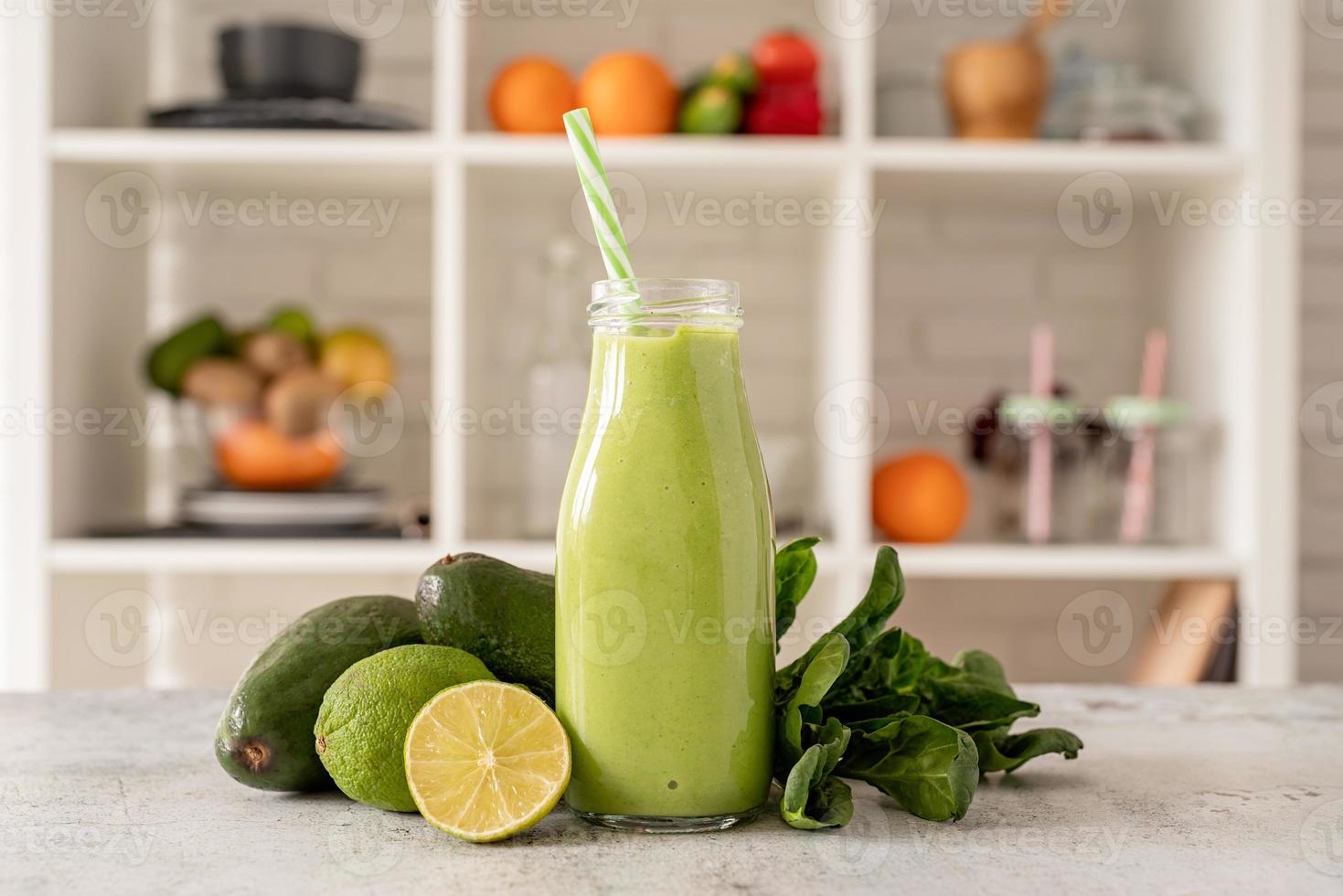 frullato di avocado e spinaci in bottiglia di vetro vista frontale sullo sfondo della cucina di casa foto