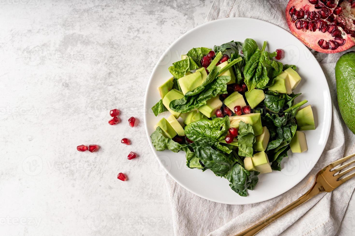 insalata con melograno, avocado, spinaci su sfondo bianco vista dall'alto piatto lay foto