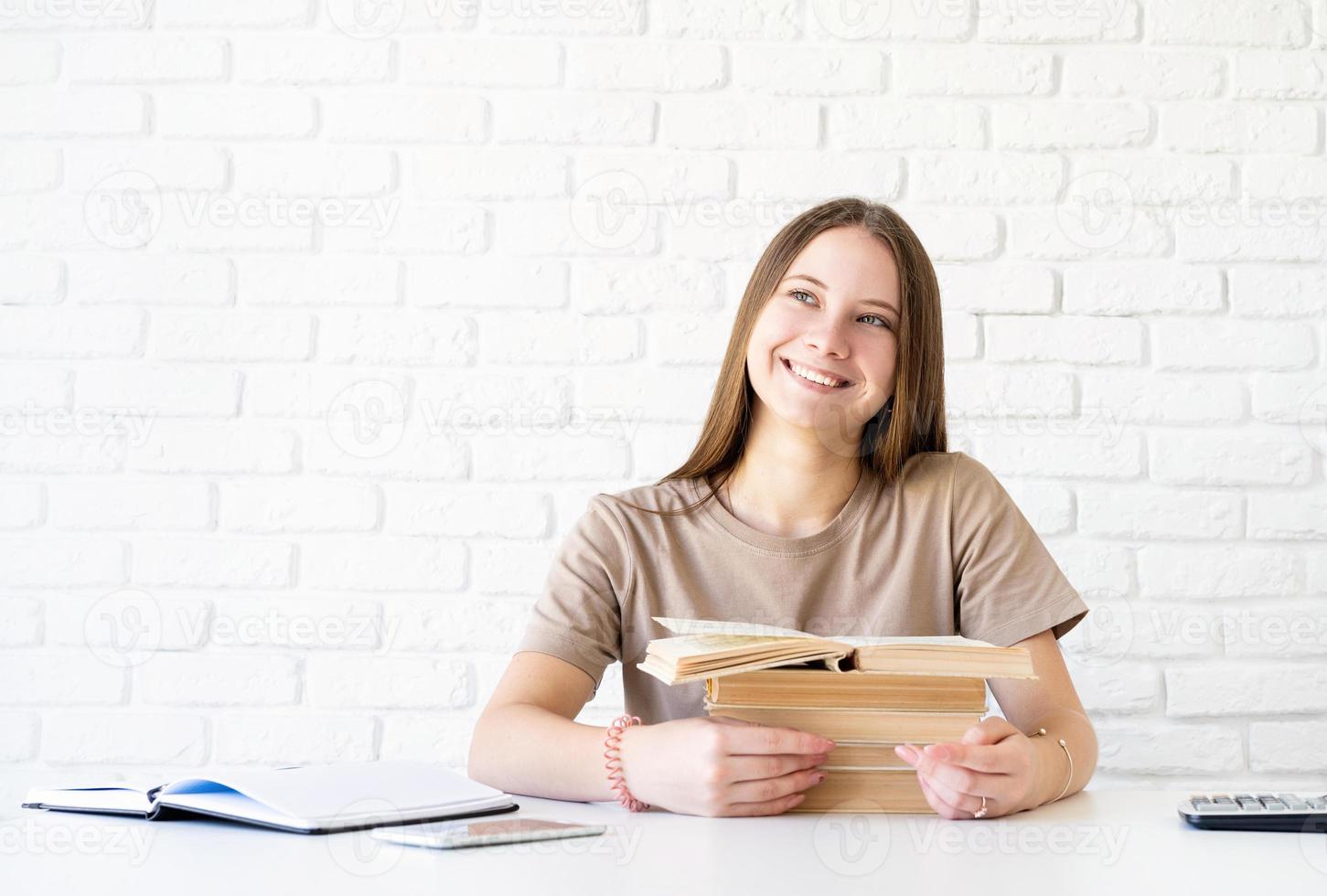 studentessa adolescente sorridente felice che tiene una pila di libri foto