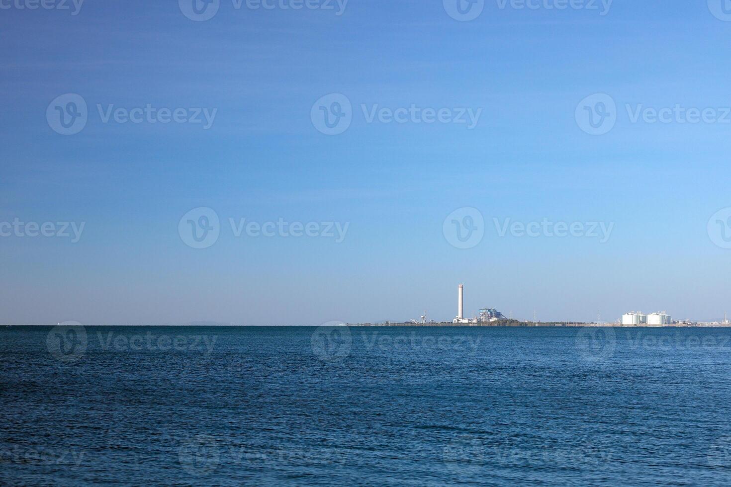 un industriale fabbrica nel il primo piano è il mare. foto