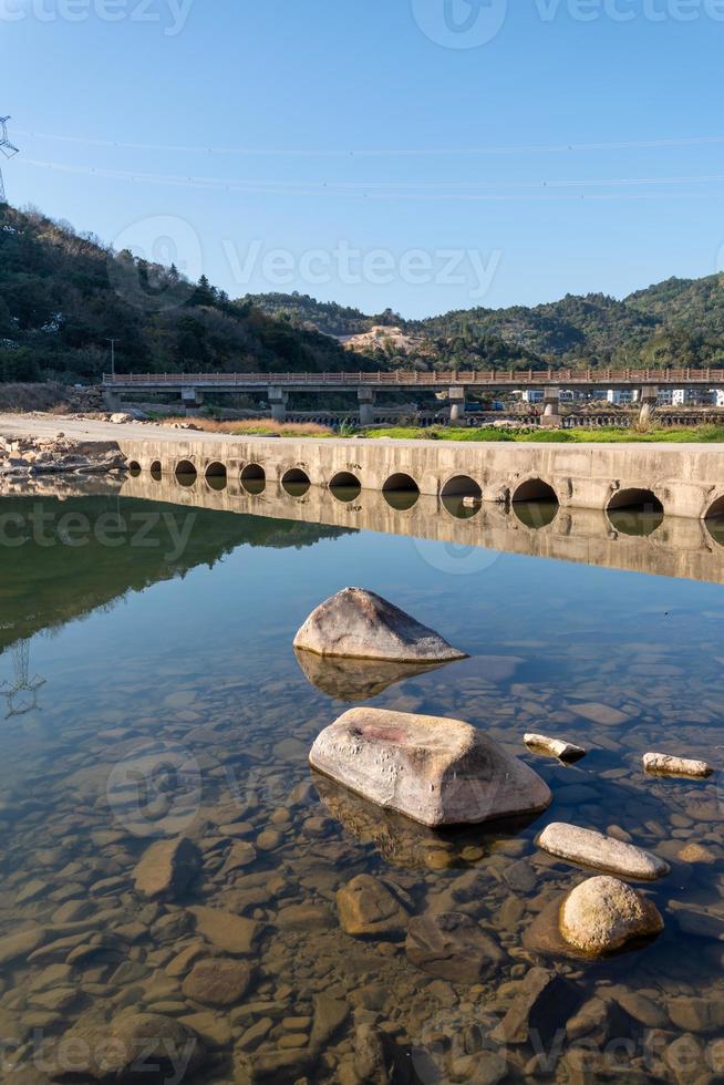 il fiume di campagna riflette la montagna, e i villaggi e le foreste sono sotto il cielo azzurro foto