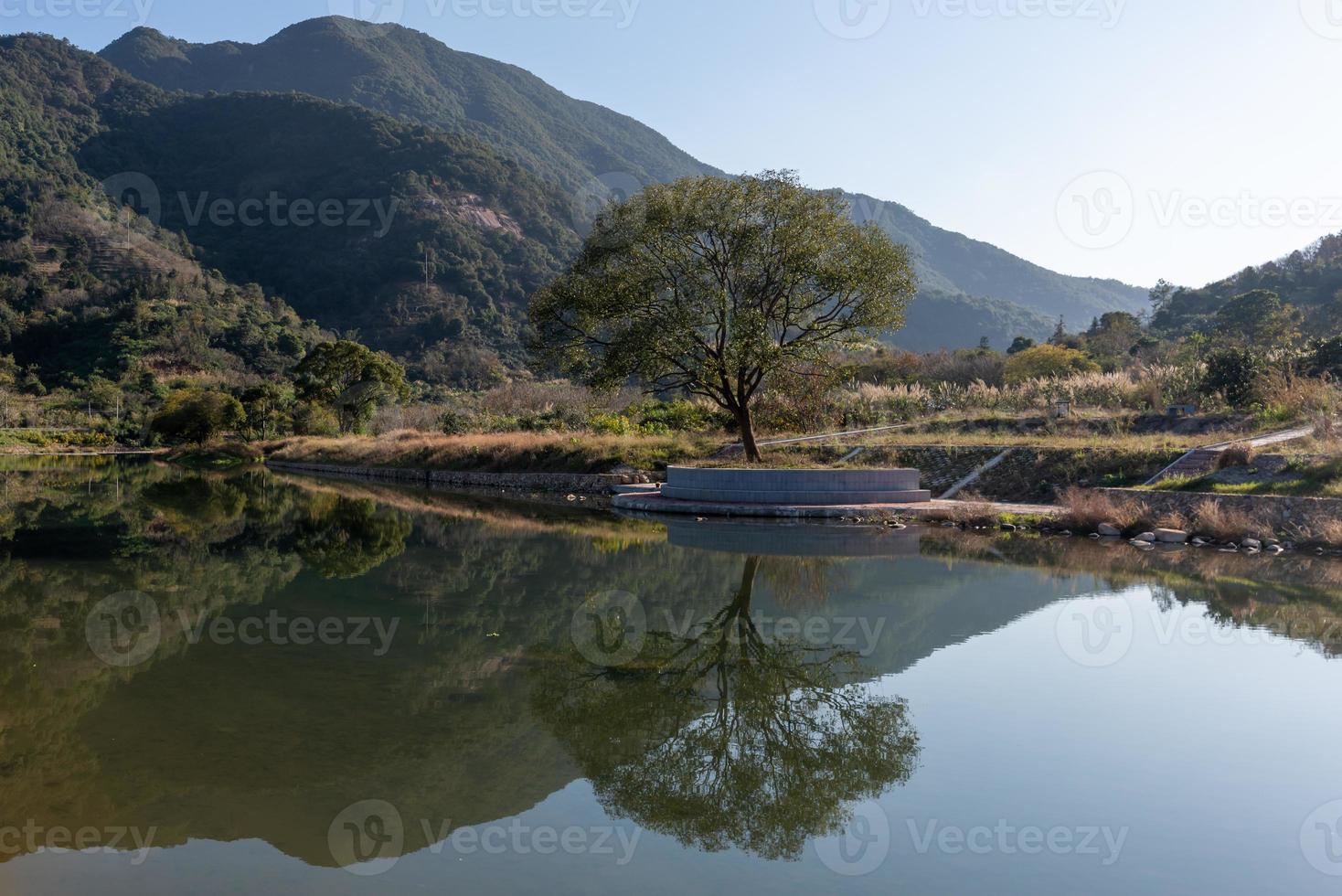 il fiume di campagna riflette la montagna, e i villaggi e le foreste sono sotto il cielo azzurro foto