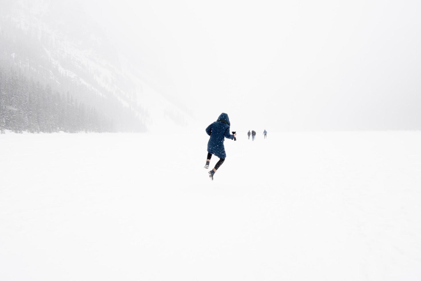 giovane che salta in aria in un paesaggio invernale con la neve. Lago Ghiacciato Louise, Parco Nazionale di Banff, Canada foto