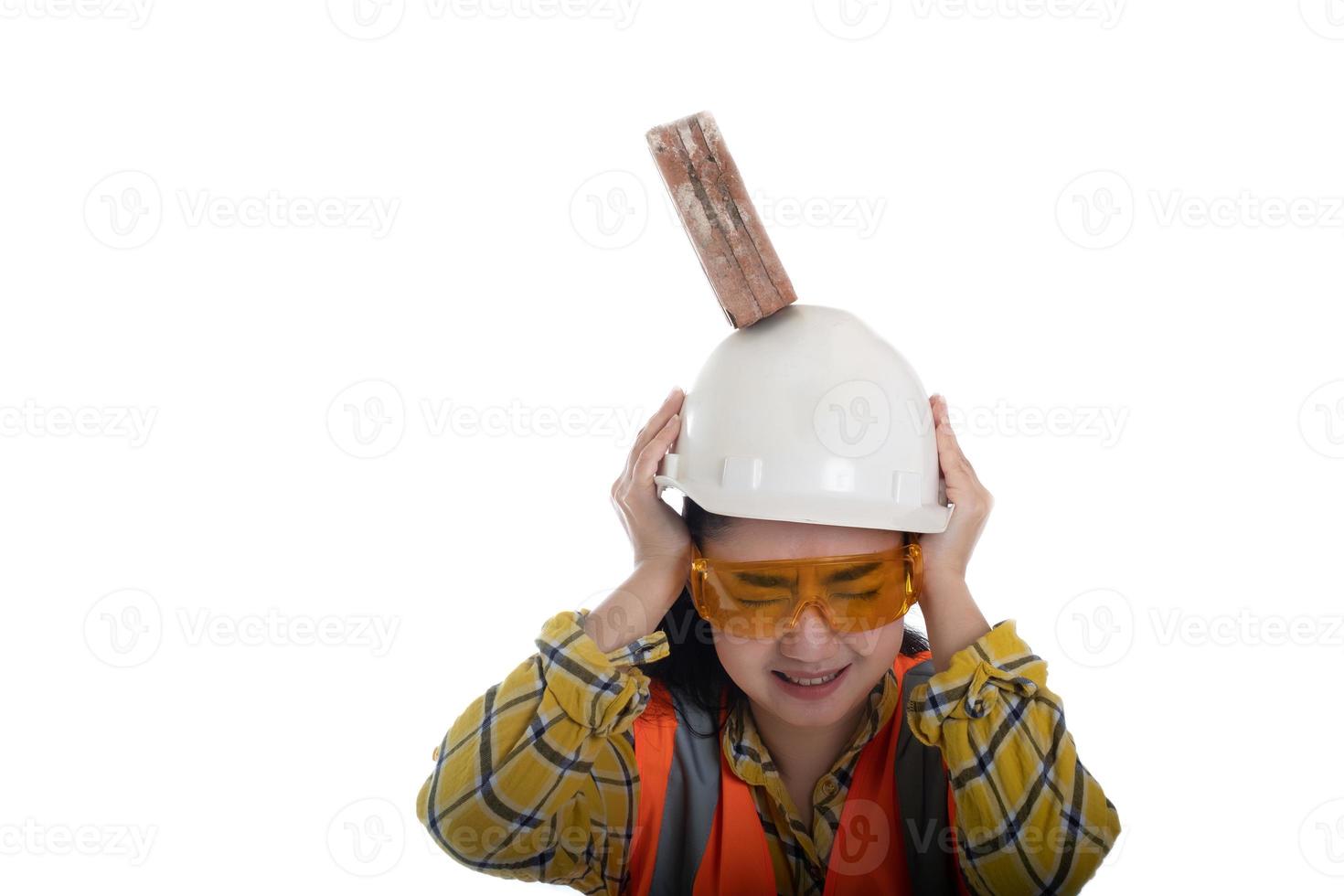 il mattone del blocco del bastone è caduto sulla testa della giovane donna dell'ingegnere asiatico sul lavoratore del casco a sfondo bianco, primo concetto di sicurezza della costruzione dell'area foto